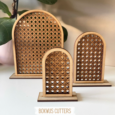 Três suportes de madeira com padrão trançado em rattan e uma planta em vaso rosa no fundo