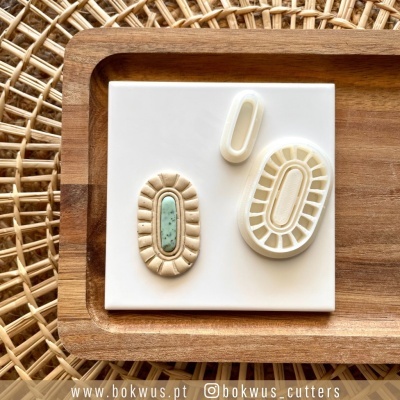 Moldes de corte de massa ovais em plástico branco e bege sobre placa branca e bandeja de madeira