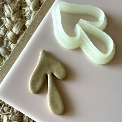 Cortador de bolachas em forma de coração partido com forma de massa ao lado em fundo rosa claro