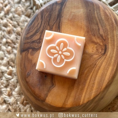 Cortador de massa quadrado com padrão floral em relevo sobre base de madeira