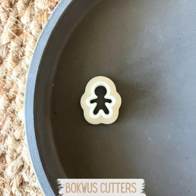 Cortador de bolacha em forma de boneco bege em prato cinzento