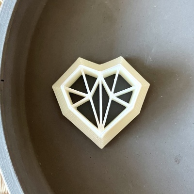 Objeto decorativo em forma de coração geométrico branco sobre fundo cinzento