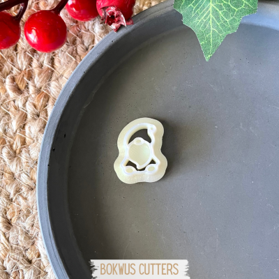 Cortante plástico branco em forma de carrinho sobre base cinzenta com decoração natural