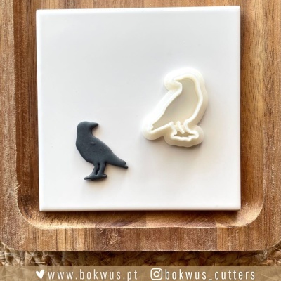 Cortador e forma de pássaro sobre azulejo branco e tabuleiro de madeira