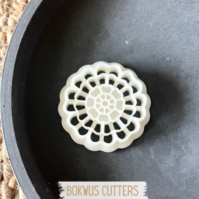 Cortador de massa branco com padrão floral em travessa preta