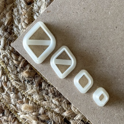 Quatro cortadores brancos em forma de losango dispostos em madeira clara com tapete de fibras naturais ao lado