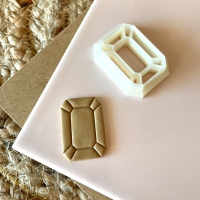 Matriz plástica branca e peça bege em superfície rosa claro e base trançada