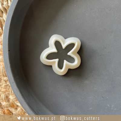 Cortador de massa em forma de flor de plástico branco numa superfície cinza