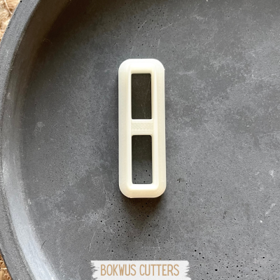 Cortador de bolachas branco com duas janelas retangulares sobre prato cinza