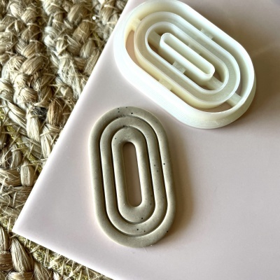 Dois clips de papel ovais em plástico branco e cinza sobre fundo cor-de-rosa e corda trançada