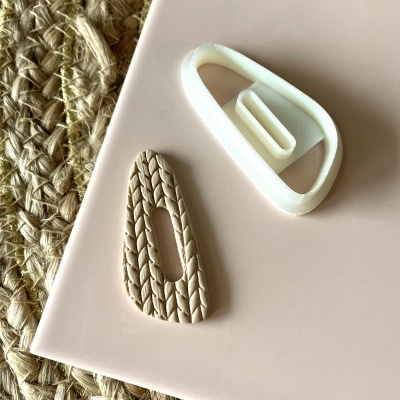 Prendedor de cabelo bege com padrão tricô e molde branco de plástico sobre superfície rosa com tapete de corda