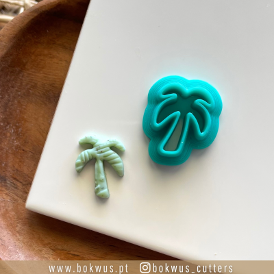 Cortador de biscoitos azul em forma de palmeira com biscoito verde texturizado ao lado