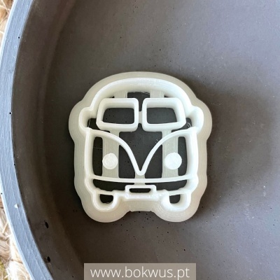 Cortador de bolachas branco em forma de carrinha dentro de um recipiente cinza