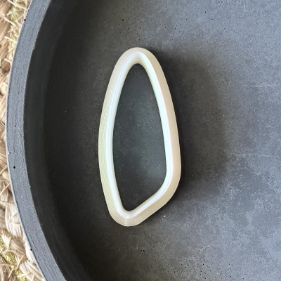 Anel decorativo branco irregular numa bandeja escura