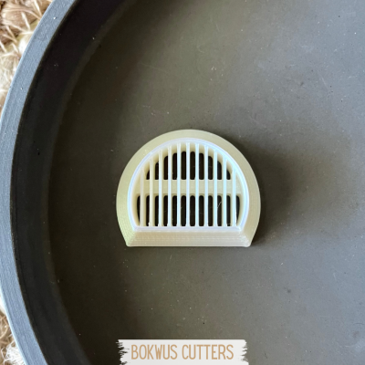 Cortador de pão branco em plástico semicircular com barras verticais numa superfície preta