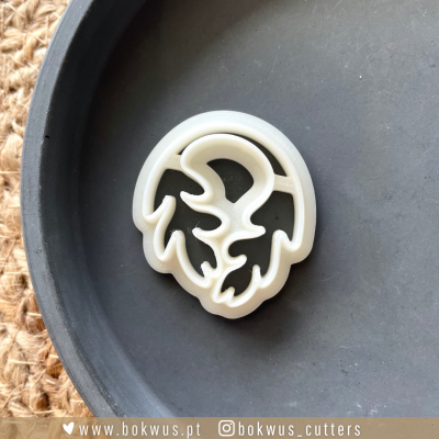 Cortador de biscoitos branco em forma de folha dentro de um prato cinzento