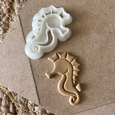 cortador de massa branco em formato de cavalo-marinho com peça de massa dourada moldada igual