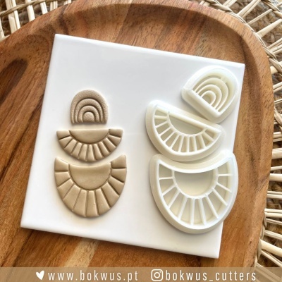 Cortantes de massa em arcos com subdivisões em branco e bege sobre base branca em prato de madeira