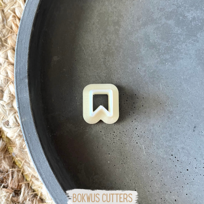 Cortador de biscoitos branco em formato de marcador sobre prato cinza