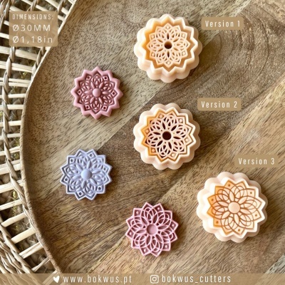 Seis cortadores de bolachas decorativas florais em cores creme, roxo, lilás e rosa num prato de madeira com base de vime