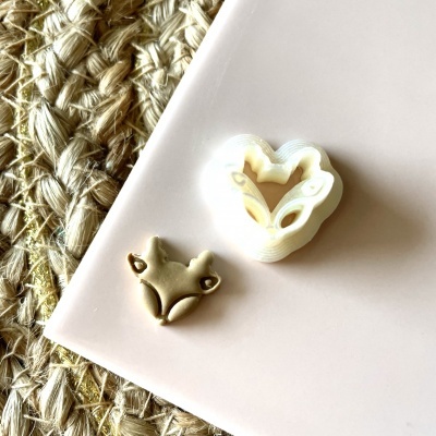 Formador cortador de raposa em plástico branco com massa dourada em fundo rosa e ráfia