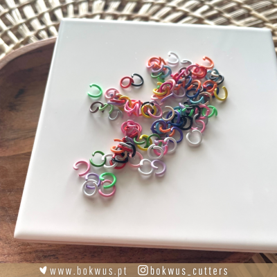 Pequenos ganchos coloridos sobre caixa branca