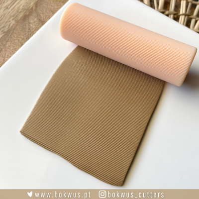 Rolo de massa creme e massa marrom clara texturizada sobre superfície branca