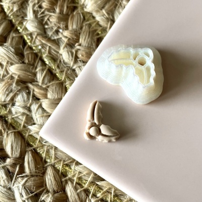 Dois objetos pequenos em superfície rosa com fundo de fibras naturais entrelaçadas