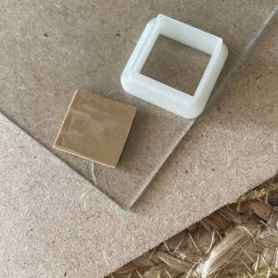 Peças quadradas branca plástica e dourada sobre superfície de pedra clara