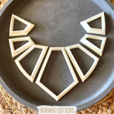 Conjunto de cortadores brancos em formas geométricas, prato cinza e texto BOKWUS CUTTERS