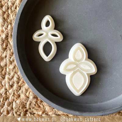 Dois cortadores de massa brancos em plástico com forma de pétalas num prato cinzento fosco