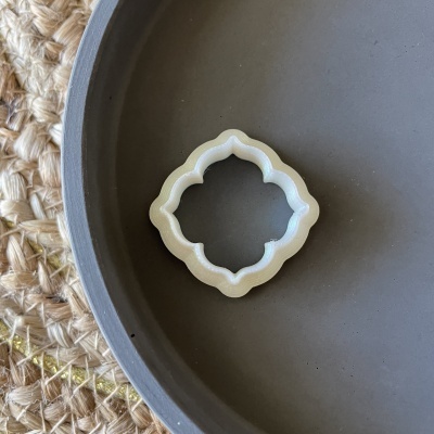 Anel decorativo branco em prato cinzento com fundo de tecido rústico.
