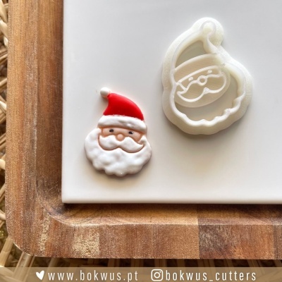 Cortador de biscoitos Pai Natal branco e biscoito decorado vermelho, branco e bege numa tábua de madeira