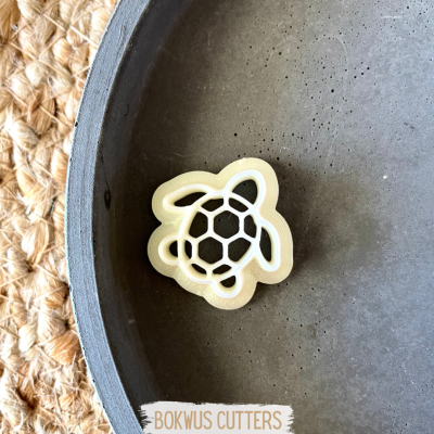 Cortante de tartaruga amarelo dentro de tigela cinza sobre tapete trançado