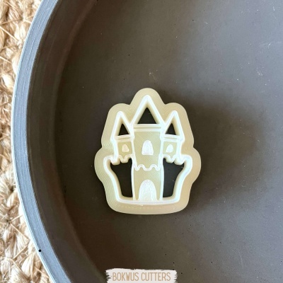 Cortador de biscoitos em forma de castelo creme numa tigela cinza sobre tecido trançado