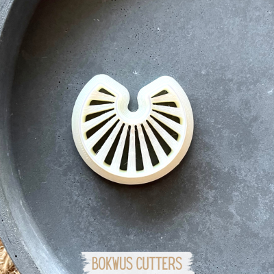 Cortador branco semicircular com aberturas radiais sobre superfície escura