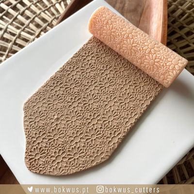 Rolo de cozinha com padrão floral gravado em massa sobre um prato branco