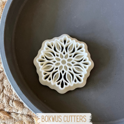 Cortador de biscoitos branco com padrão floral numa tigela cinzenta