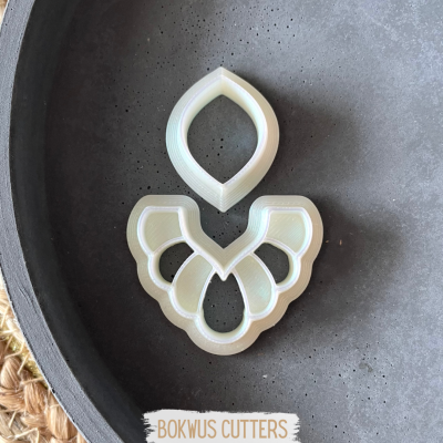 Dois cortadores de plástico branco em superfícies preta e tapete de fibras naturais