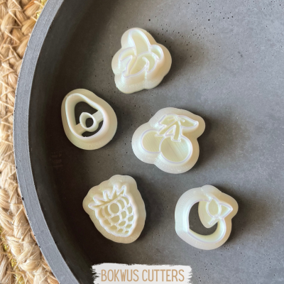 Cortadores de massa em forma de frutas brancos sobre uma superfície cinza