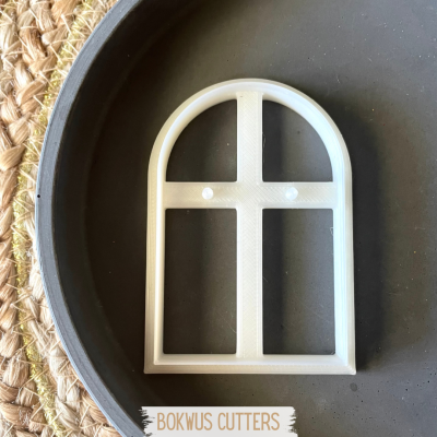 Cortador de forma de janela arqueada em plástico branco dentro de um prato cinzento sobre tapete de palha.
