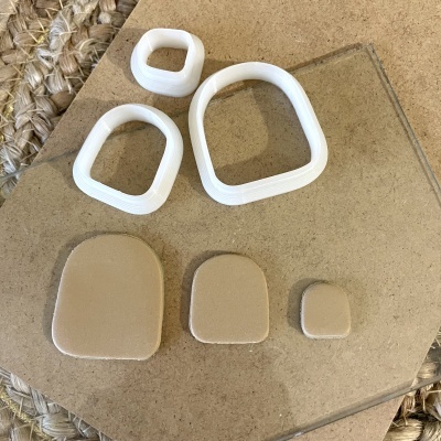 Conjunto de moldes e peças em polímero branco e bege com formato quadrado arredondado sobre base clara