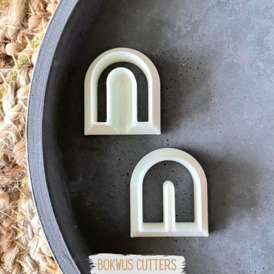 Dois cortadores de bolacha brancos em forma de arco numa superfície cinzenta redonda.