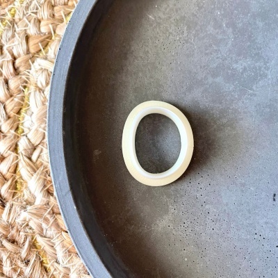 Anel branco em prato cinza sobre tapete de palha