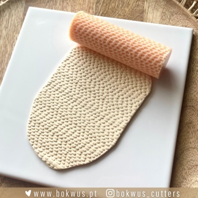 Rolo de massa texturizado em silicone pêssego com massa branca texturizada sobre placa branca