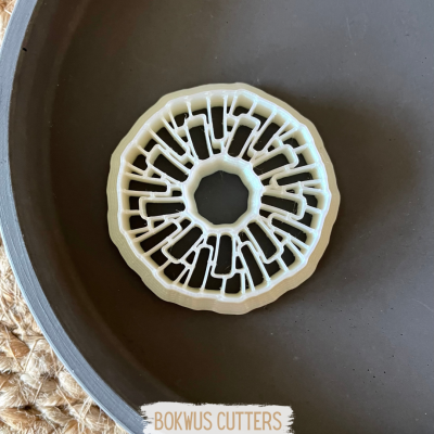 Cortante circular branco sobre prato escuro com etiqueta BOKWUS CUTTERS