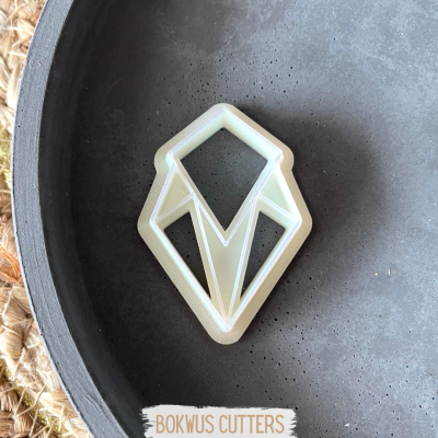 Cortador de bolacha geométrico bege num prato cinza com rótulo BOKWUS CUTTERS