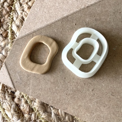 cortador de plástico branco e massa bege em formato irregular sobre madeira e tapete de corda trançada