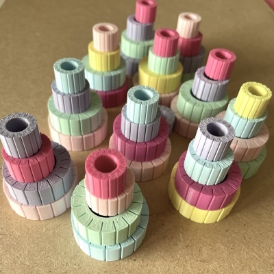 Torres de anéis coloridos empilhados em cores pastel sobre fundo castanho