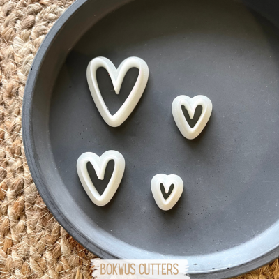 Conjunto de quatro cortadores brancos em forma de coração num prato cinza escuro
